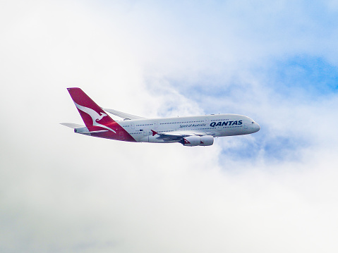 Australia: QANTAS A380 flying through a mostly cloudy sky.