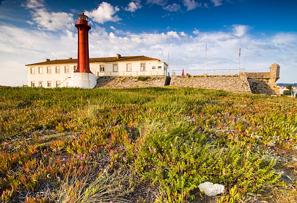 Aveiro, Portugal - July 31, 2011: People sunbathing on the Barra beach in summer, with the Aveiro lighthouse in the background. Is the tallest lighthouse in Portugal and highlighted by flashing lights in two different colors: white and green