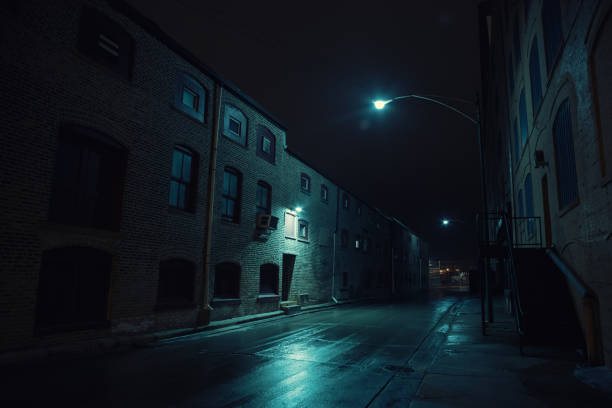 dark urban city alley at night after a rain featuring vintage warehouses. - crime scene imagens e fotografias de stock