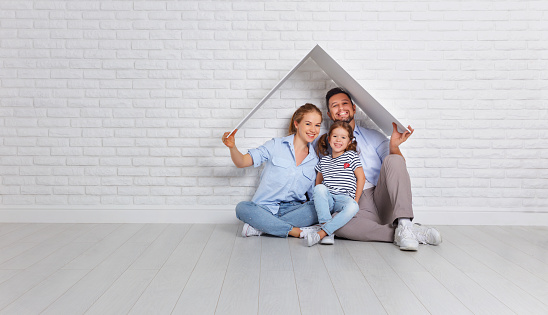 concept housing a young family. Mother father and child in new house with a roof at empty brick wall