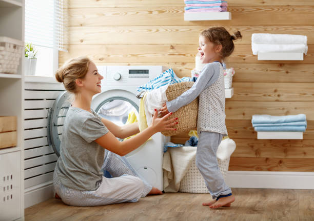 szczęśliwa matka rodzinna gospodyni domowa i dziecko w pralni z pralką - stereotypical housewife little girls family domestic kitchen zdjęcia i obrazy z banku zdjęć