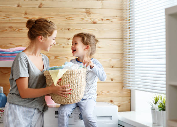 szczęśliwa matka rodzinna gospodyni domowa i dziecko w pralni z pralką - stereotypical housewife little girls family domestic kitchen zdjęcia i obrazy z banku zdjęć