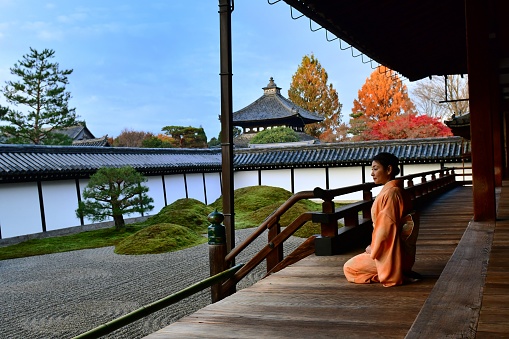 A Japanese woman, in her 40’s, in kimono is appreciating Japanese rock garden at Hojo (the former living quarters of the head priest) of Tofuku-ji Temple in Kyoto. This garden is called Eastern Garden, the largest of the four gardens surrounding Hojo and it is composed of four rock groups symbolizing Elysian islands on the rough seas.