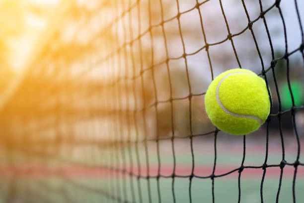 テニス ボール上のネットに当たって裁判所背景をぼかし - tennis equipment ストックフォトと画像