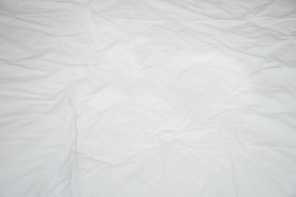 istock Old rumpled bed sheet with creases. View from above 914376684
