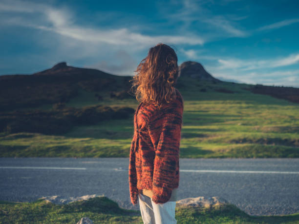 istock Young woman standing by road in wilderness 914379256