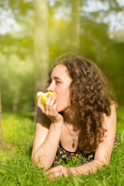istock Young pretty woman eating apple on a field 914415394