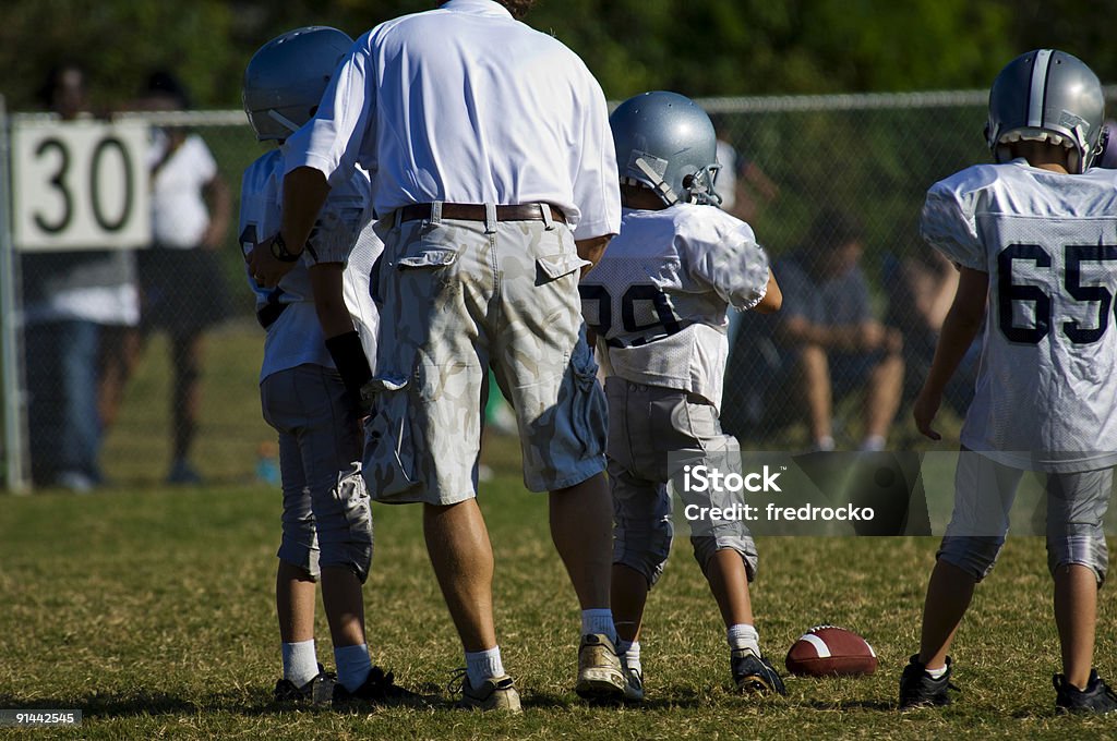 Entrenador de fútbol enseñar Football Players durante un juego de fútbol americano - Foto de stock de Fútbol americano - Pelota libre de derechos