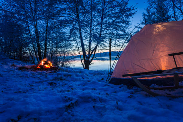 istock Campfire and tent by the lake at dusk in winter 914432192