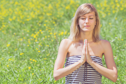 Young woman doing yoga on a flowerly meadow.