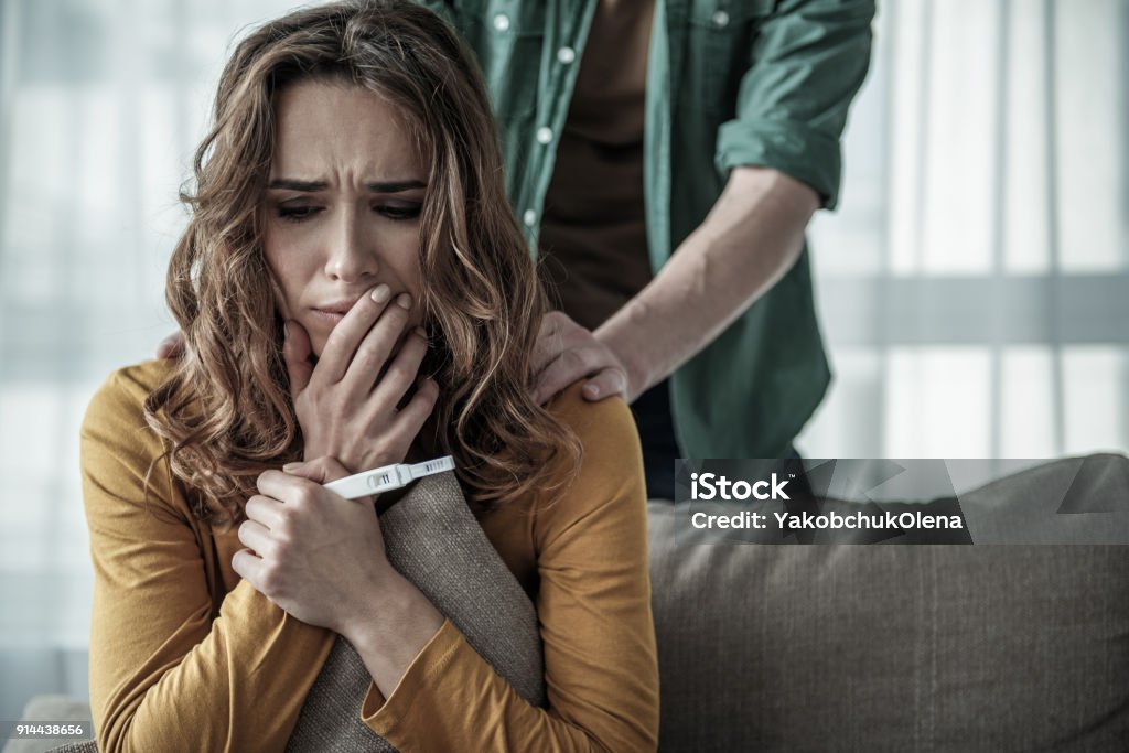 Couple deciding to abort female pregnancy There is only one way. Portrait of pregnant woman thinking about abortion. Man is standing behind her and touching her shoulder Pregnant Stock Photo