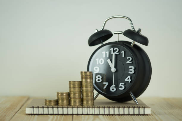 istock Steps of coins stack with vintage alarm clock and pen, notebook paper on wooden working table with copy space for text, financial and business planning concept. 914443094