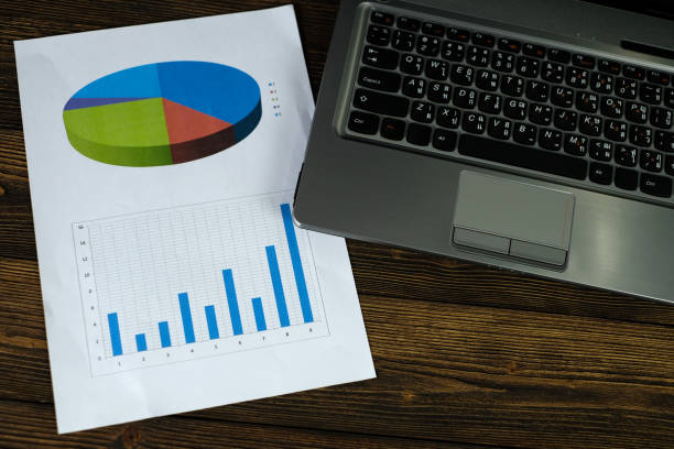istock Notebook laptop computer and financial graph on white paper on working table, business planning vision and finance analysis concept. 914443248