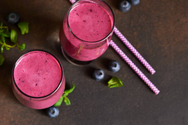 smoothies with a banana, raspberries and blueberries on a dark background. detox drink. - blueberry smoothie milk shake drink imagens e fotografias de stock