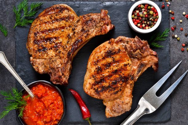 istock Grilled beef steak with spices and tomato sauce on a stone board. 914444126