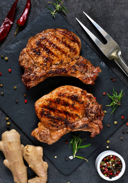 istock Grilled beef steak with spices and tomato sauce on a stone board. 914444156