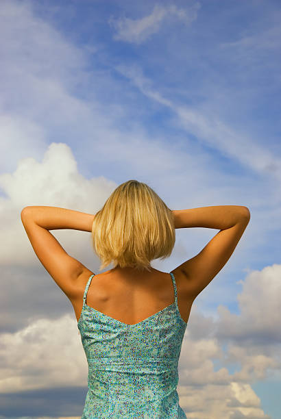 chica rubia desde detrás azul nublado cielo de fondo - blond hair overcast sun sky fotografías e imágenes de stock