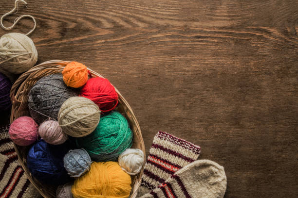 warm socks created from natural wool for cold weather. knitting balls in the basket on a brown rustic table. grandmother made socks for children. womanly hobby. knitting concept. empty place for text. - womanly imagens e fotografias de stock