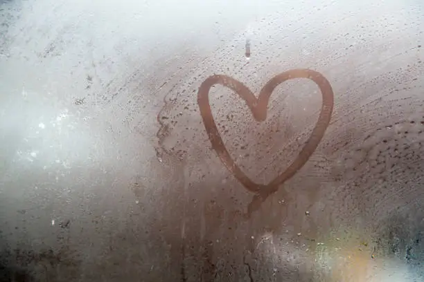 Photo of A heart painted on a misted window.Heart on misted glass.