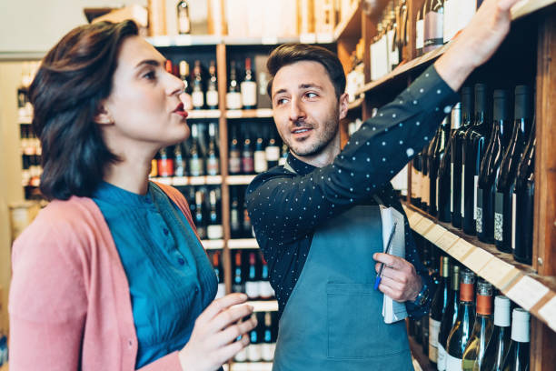 istock Young man assisting a customer in a wine shop 914478434