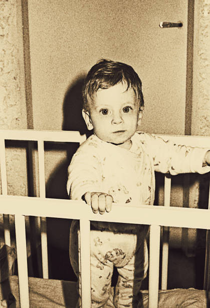 Vintage baby boy looking at camera vintage toned and grainy photo from the sixties baby boy looking at camera crib photos stock pictures, royalty-free photos & images