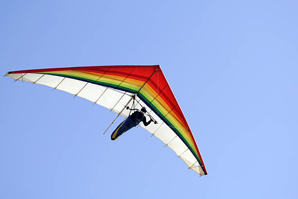 A person hang gliding on a clear day Hang glider with clear blue sky,San Francisco,Ca. Rainbow colors.Click for more action. gliding photos stock pictures, royalty-free photos & images