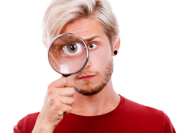 istock man holds on eye magnifying glass looking through loupe 914486068