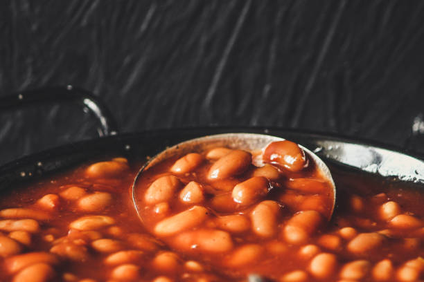 istock Beans in tomato sauce on a frying pan - Serving on a wooden table 914490210