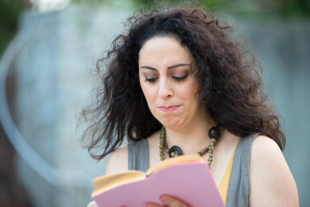 istock Beautiful Woman Reading A Book With A Sad Face 914497964