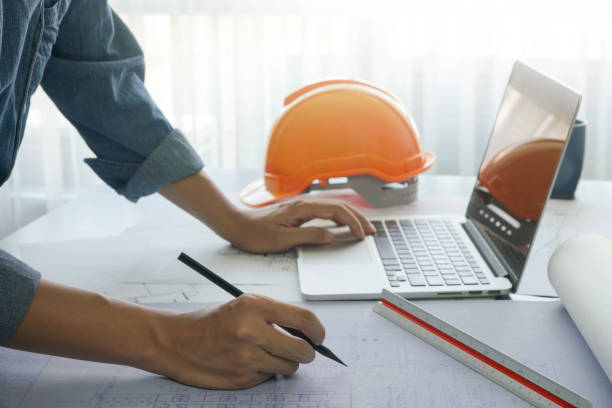 istock architect working with sketch on blueprint of construction in office, computer laptop and construction tools on wooden table 914520066