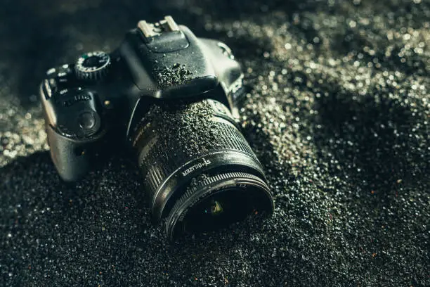 DSLR camera in black sand. Modern professional photo camera