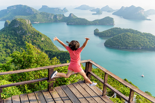 Woman tourist jumping with happy it has reached the peak mountain to see the beautiful natural landscape of sea from view point of Ko Wua Ta Lap island in Mu Ko Ang Thong, Surat Thani, Thailand