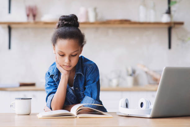 mała dziewczynka czyta książkę w domu - wireless technology serious education enjoyment zdjęcia i obrazy z banku zdjęć