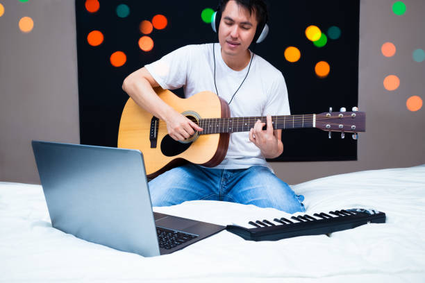 istock asian male musician composing a song, practicing guitar with online music lesson 914526982