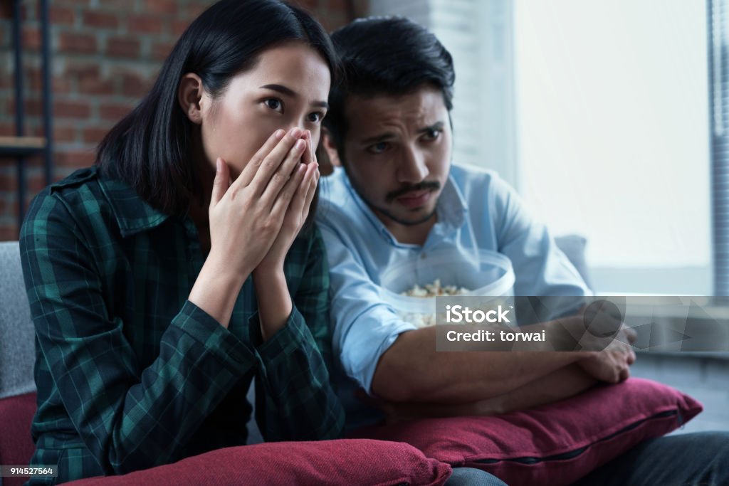Couples are watching movies at home. He's thrilled with the movie. Couple - Relationship Stock Photo