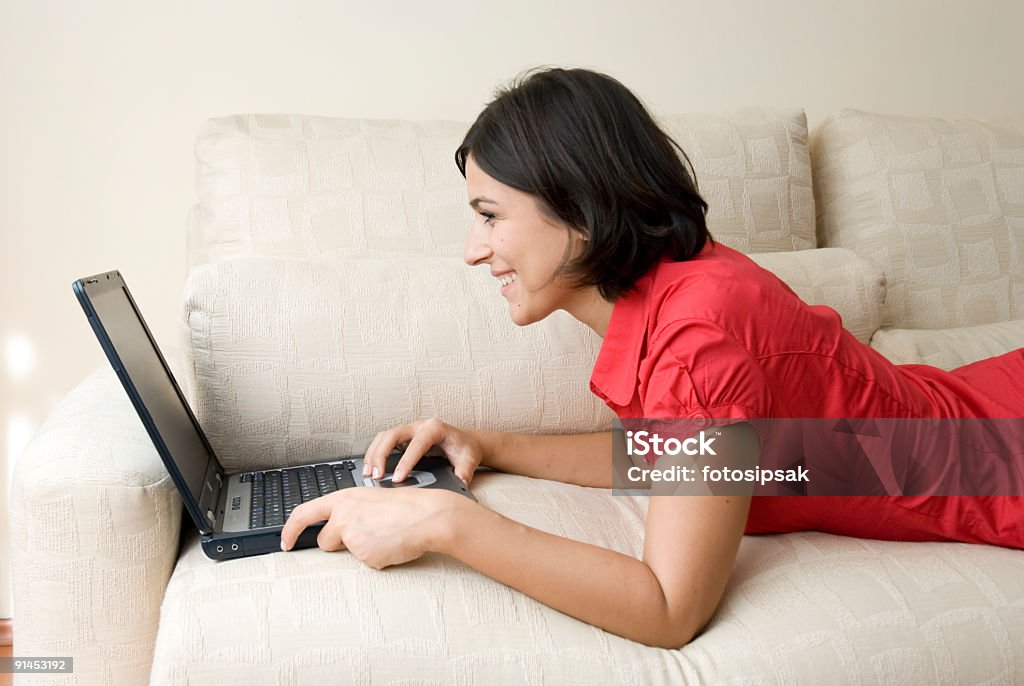 cheerful woman using laptop computer at home happy smiling young woman using laptop computer on the sofa at home 20-29 Years Stock Photo