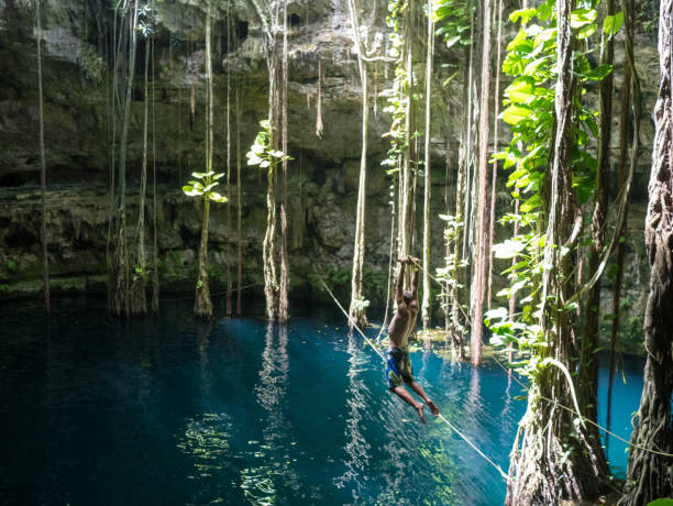 istock Young man rope swinging into Cenote sink hole Oxman 914540852