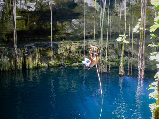 istock Young man rope swinging into Cenote sink hole Oxman 914540856