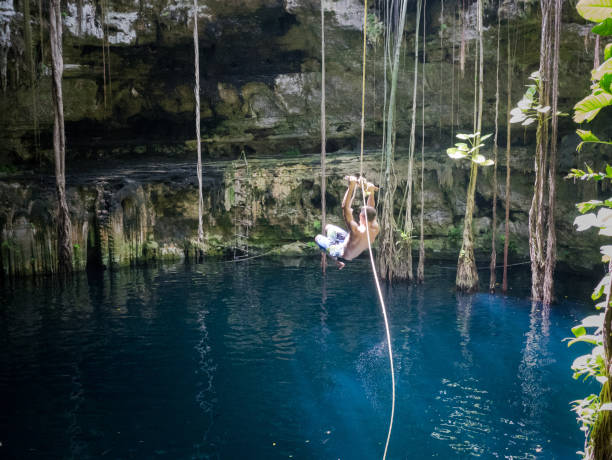 istock Young man rope swinging into Cenote sink hole Oxman 914540860
