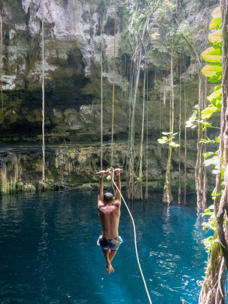 istock Young man rope swinging into Cenote sink hole Oxman 914540870