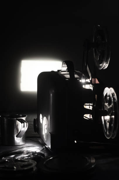 istock Old cinema projector and a glowing screen in the dark 914545956