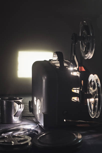 istock Old cinema projector and a glowing screen in the dark 914545982