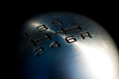 This DSLR color image is of a chrome gear shift knob in a sports car. the gear shift knob has 6 gears on the knob and is made of shiny chrome metal. the image is a macro of the chrome gear shift knob. the image represents speed, fast and luxury. 