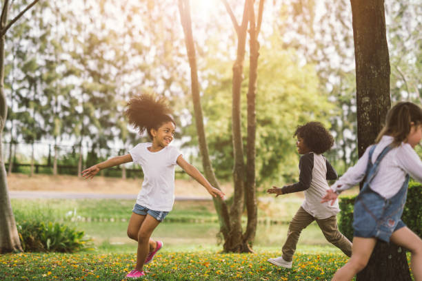 маленькая девочка играет на открытом воздухе - little girls group of people happiness cheerful стоковые фото и изображения