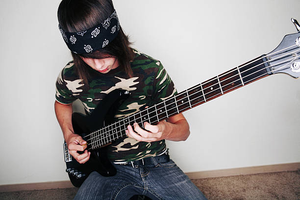 Camouflage Teen Male Playing Bass Guitar in Jeans stock photo