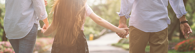 Happy family mother father and daughter walk on nature on sunset hold hand