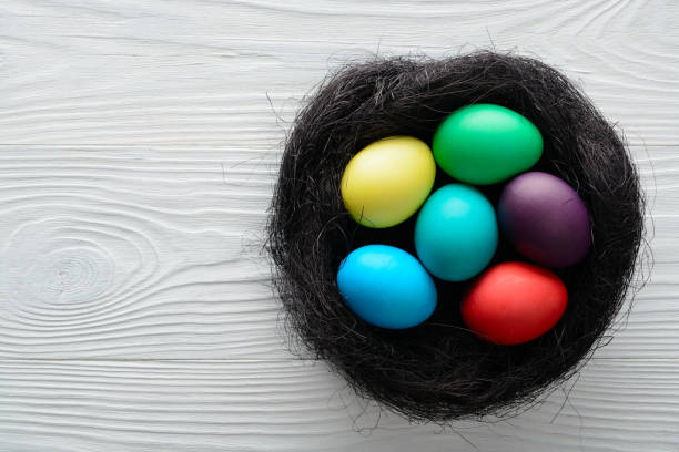 istock Multicolored Easter eggs in a nest on the wooden table. Top view with copy space 914562082