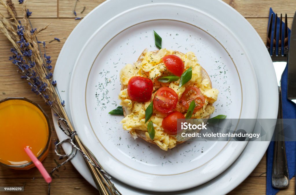 Scrambled eggs and tomato on bagel Scrambled eggs and tomato on bagel with a glass of juice Egg - Food Stock Photo