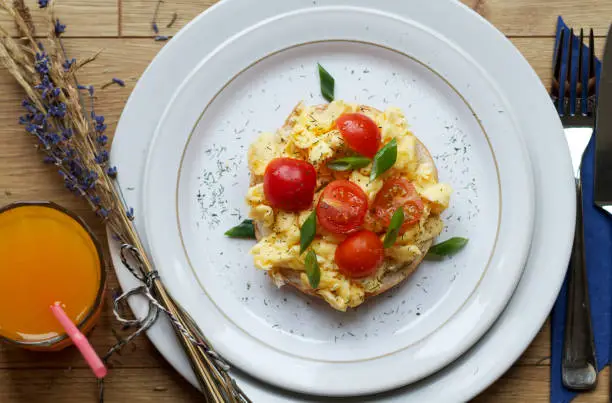 Photo of Scrambled eggs and tomato on bagel