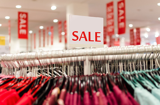 sale of clothing, spring discount of winter clothes, clothes on the hook in the mall with lot sale sign